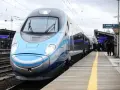 Nowoczesny, niebiesko-szary pociąg Pendolino stoi na peronie.
