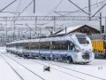 Pociąg PKP Intercity pokryty lodem i śniegiem, stojący na zaśnieżonych torach. Utrudnienia w ruchu kolejowym z powodu zimy.
