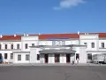 Dworzec PKP Ełk z czerwonym dachem i napisem "Dworzec Kolejowy". Obok hostel.