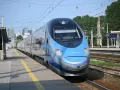 Niebiesko-srebrny pociąg Pendolino na peronie dworca kolejowego.