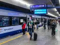 Ludzie na peronie PKP Intercity, gotowi do podróży. Może ktoś właśnie sprawdza, czy dopłata do biletu ulgowego PKP jest konieczna.