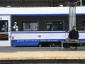 Kobieta z walizką czeka na pociąg PKP Intercity, szukając tanich biletów.