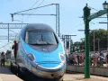 Błękitno-szary pociąg Pendolino na peronie, ludzie czekają na podróż. Oznaczenie Pendolino w rozkładzie jazdy.