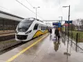 Nowoczesna hulajnoga elektryczna czeka na podróż w pociągu na mokrym peronie.