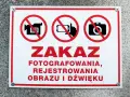Tabliczka z czerwonym obramowaniem informuje o zakazie fotografowania, rejestrowania obrazu i dźwięku.