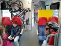 W pociągu Kolei Mazowieckich rowerzyści podróżują z rowerami. Dzieci i dorośli siedzą obok.