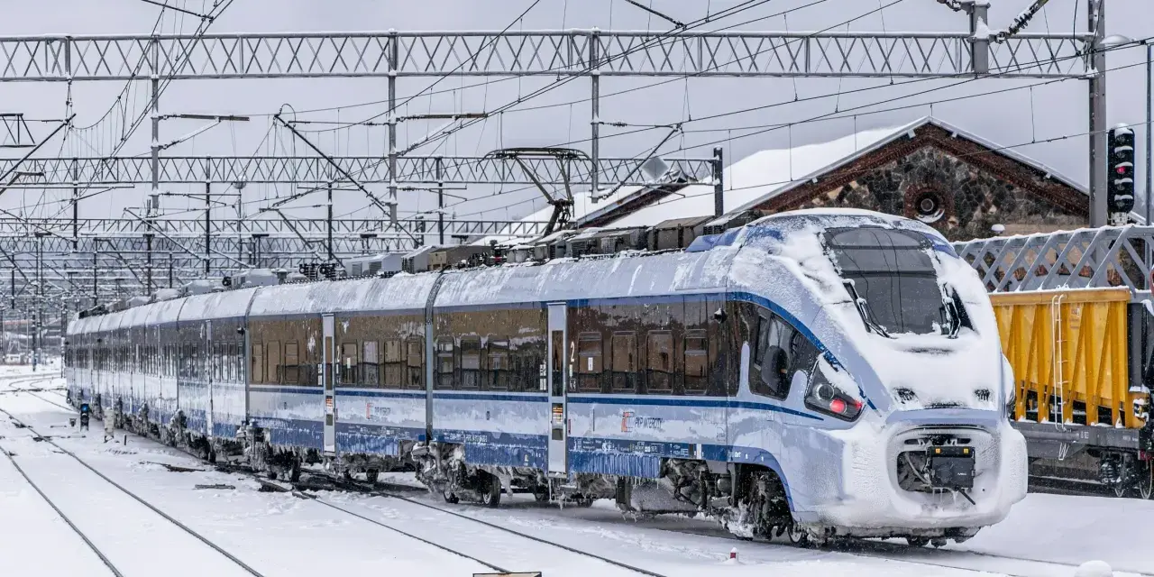 Pociąg PKP Intercity pokryty lodem i śniegiem, stojący na zaśnieżonych torach. Utrudnienia w ruchu kolejowym z powodu zimy.