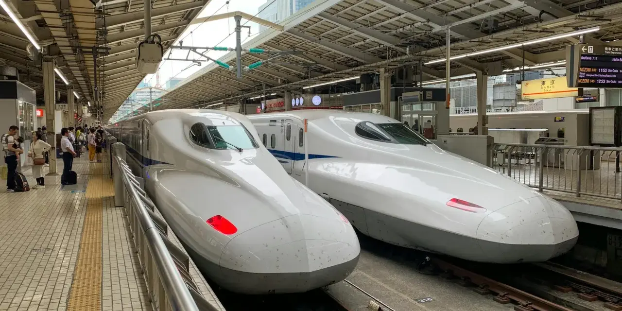 Dwa białe pociągi Shinkansen stojące na peronie, gotowe do podróży.