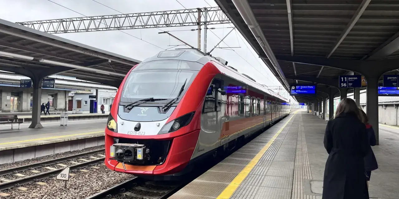 Czerwono-szary pociąg POLREGIO na peronie dworca kolejowego.