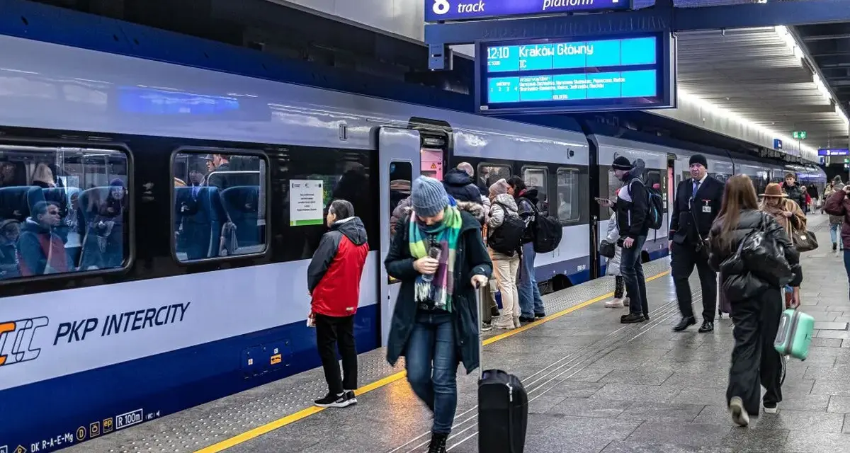 Ludzie na peronie PKP Intercity, gotowi do podróży. Może ktoś właśnie sprawdza, czy dopłata do biletu ulgowego PKP jest konieczna.