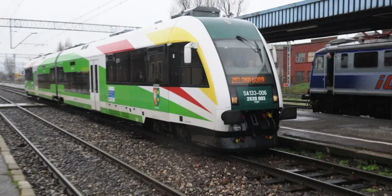 Pociąg z napisem "Zielona Góra" na torach, z zielonymi i białymi pasami na karoserii.