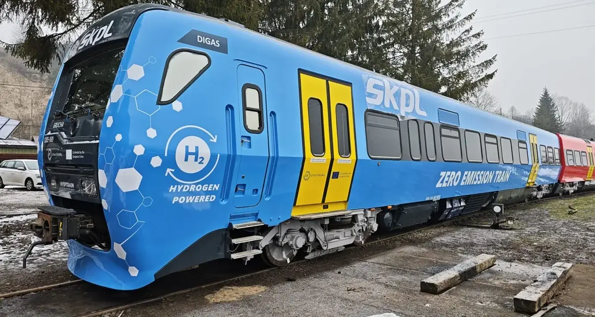 Niebieski pociąg SKPL z napędem wodorowym, oznaczony jako "ZERO EMISSION TRAIN", stoi na torach.