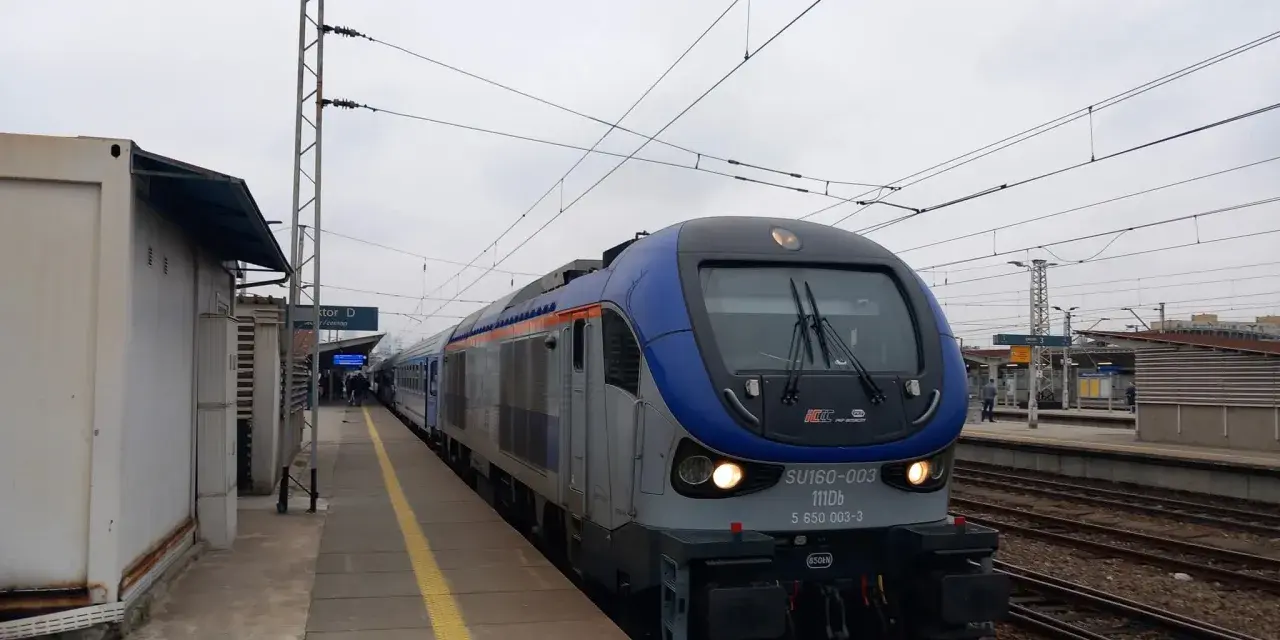 Lokomotywa PKP Intercity SU160-003 na torach kolejowych przy peronie.