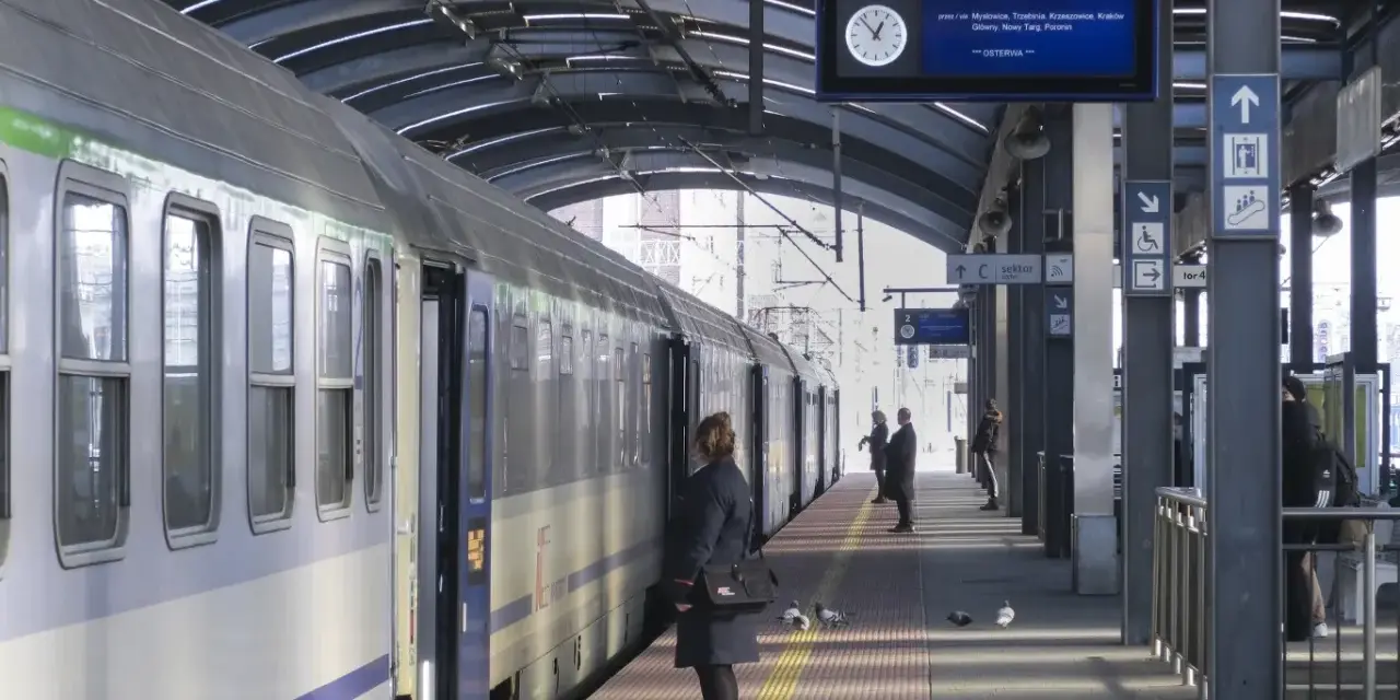 Pociąg na peronie, tablica informacyjna z trasą do Zakopanego, pasażerowie.