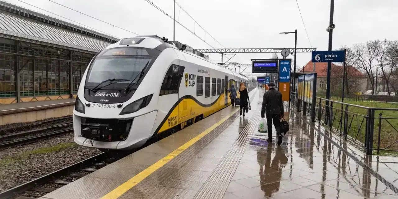 Nowoczesna hulajnoga elektryczna czeka na podróż w pociągu na mokrym peronie.