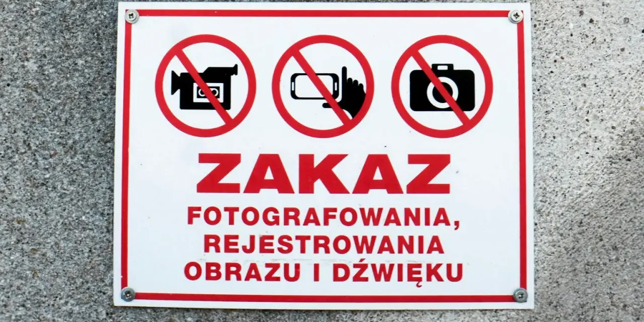 Tabliczka z czerwonym obramowaniem informuje o zakazie fotografowania, rejestrowania obrazu i dźwięku.