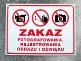 Tabliczka z czerwonym obramowaniem informuje o zakazie fotografowania, rejestrowania obrazu i dźwięku.