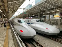 Dwa białe pociągi Shinkansen stojące na peronie, gotowe do podróży.