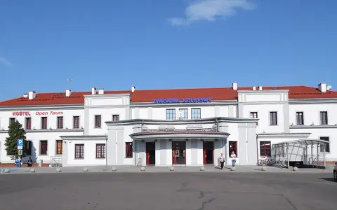 Dworzec PKP Ełk z czerwonym dachem i napisem "Dworzec Kolejowy". Obok hostel.