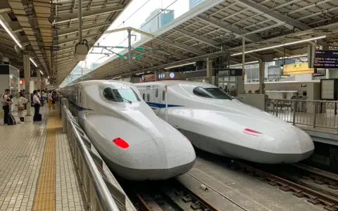 Dwa białe pociągi Shinkansen stojące na peronie, gotowe do podróży.