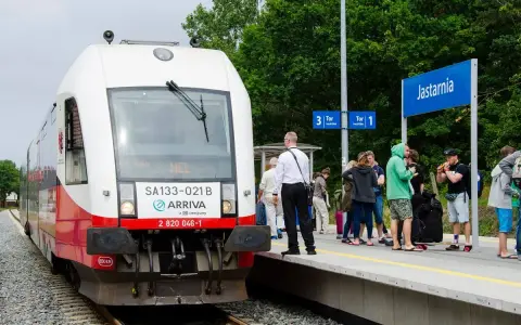 Pociąg Arriva z napisem HEL czeka na pasażerów w Jastarni. Ludzie z bagażami stoją na peronie, gotowi do podróży z Helu do Gdańska.