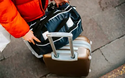 Ręce układają torbę podróżną na walizce. Zastanawiasz się, ile się płaci za nadbagaż?