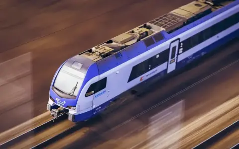 Pędzący pociąg Stadler, pokonujący trasę Białystok - Lublin, mija rozmyte krajobrazy.