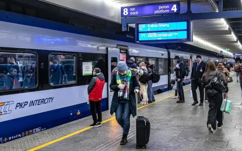 Ludzie na peronie PKP Intercity, gotowi do podróży. Może ktoś właśnie sprawdza, czy dopłata do biletu ulgowego PKP jest konieczna.