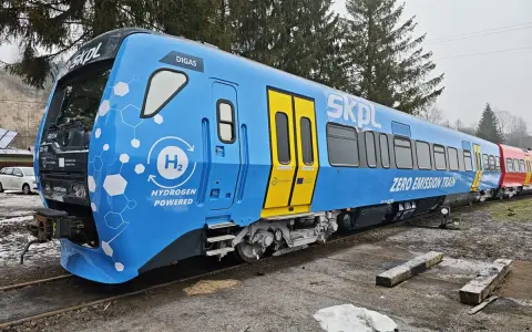 Niebieski pociąg SKPL z napędem wodorowym, oznaczony jako "ZERO EMISSION TRAIN", stoi na torach.