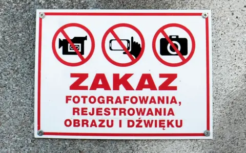 Tabliczka z czerwonym obramowaniem informuje o zakazie fotografowania, rejestrowania obrazu i dźwięku.