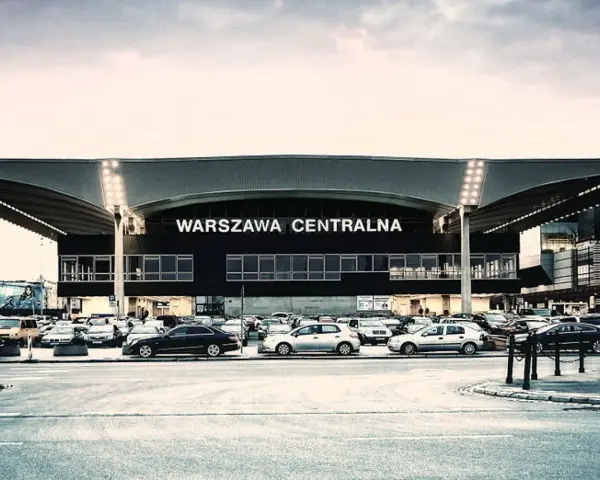 Warszawa Centralna. Po podróży pociągiem, czas na pyszne jedzenie w pobliżu dworca. Zaparkowane samochody czekają na pasażerów.