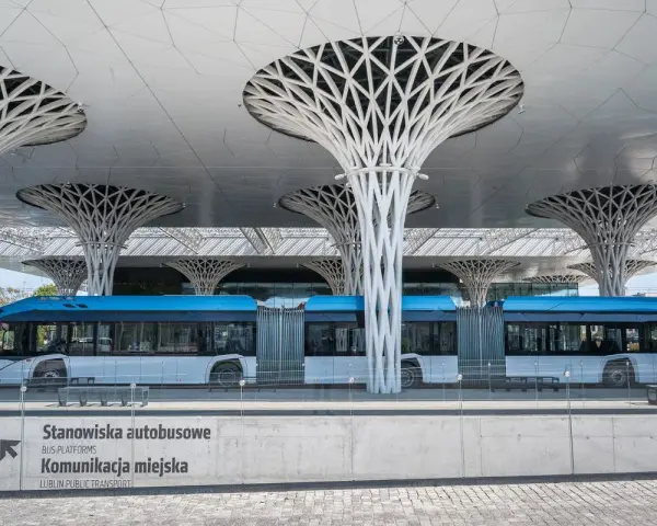 Nowoczesny dworzec autobusowy w Lublinie, z niebieskim autobusem i charakterystycznymi, drzewiastymi podporami dachu. Podróż z Lublina do Białej Podlaskiej tym środkiem transportu to czysta przyjemność.