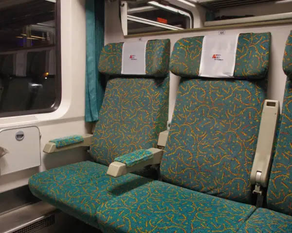 Wnętrze wagonu Intercity z zielonymi siedzeniami. Numer 46 nad zagłówkiem. Jak znaleźć wagon w pociągu Intercity?
