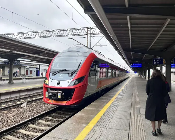 Czerwono-szary pociąg POLREGIO na peronie dworca kolejowego.