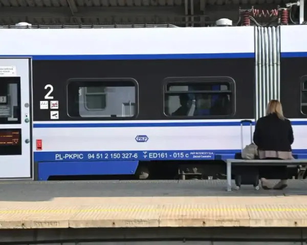 Kobieta z walizką czeka na pociąg PKP Intercity, szukając tanich biletów.