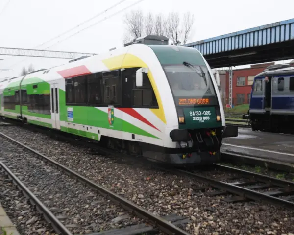 Pociąg z napisem "Zielona Góra" na torach, z zielonymi i białymi pasami na karoserii.