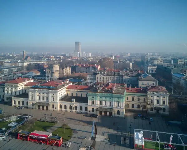 Widok na dworzec główny z tablicą "Kraków Główny". W tle miejska panorama.