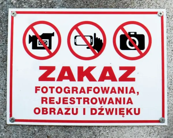 Tabliczka z czerwonym obramowaniem informuje o zakazie fotografowania, rejestrowania obrazu i dźwięku.