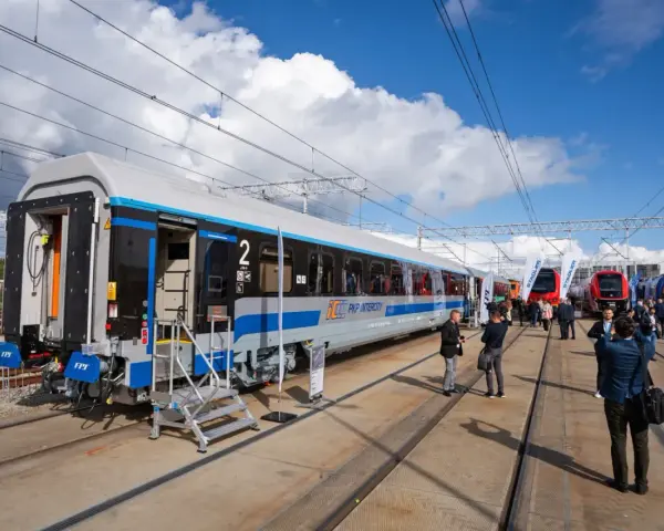Nowy wagon PKP Intercity z niebieskim pasem, gotowy na podróż. W tle inne nowoczesne składy ec.