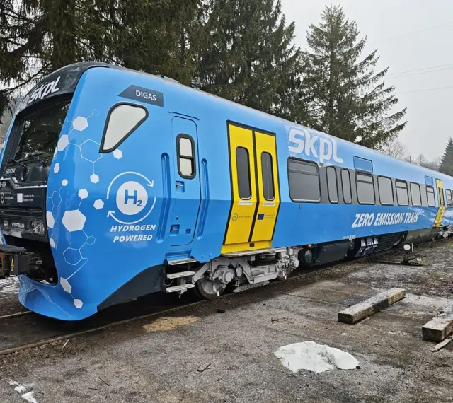 Niebieski pociąg SKPL z napędem wodorowym, oznaczony jako "ZERO EMISSION TRAIN", stoi na torach.