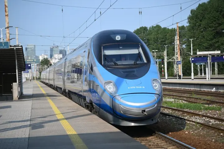 Niebiesko-srebrny pociąg Pendolino na peronie dworca kolejowego.