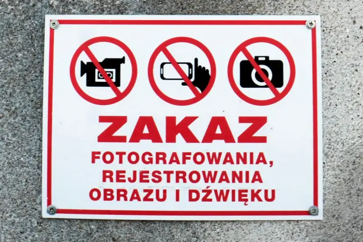 Tabliczka z czerwonym obramowaniem informuje o zakazie fotografowania, rejestrowania obrazu i dźwięku.