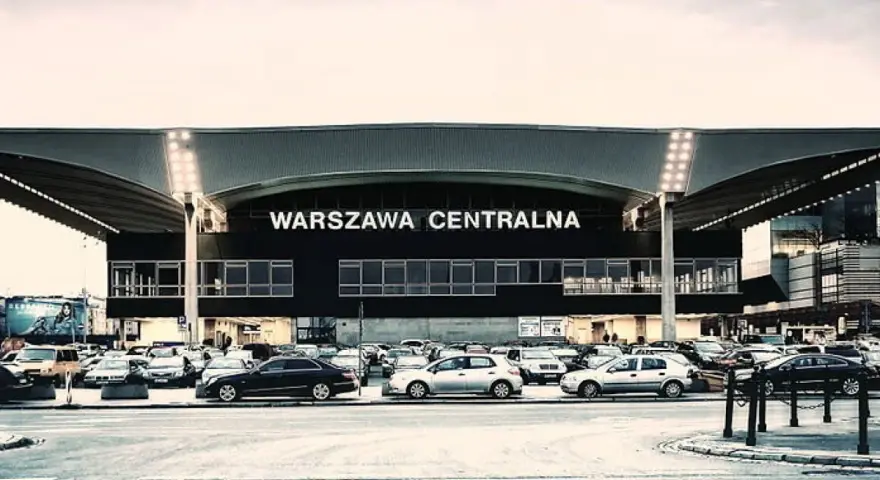 Warszawa Centralna. Po podróży pociągiem, czas na pyszne jedzenie w pobliżu dworca. Zaparkowane samochody czekają na pasażerów.