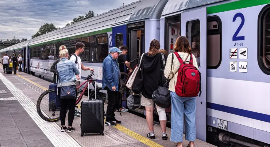 Ludzie z bagażami i rowerami czekają na pociąg PKP. Może właśnie skorzystają ze zniżki PKP na podróż?