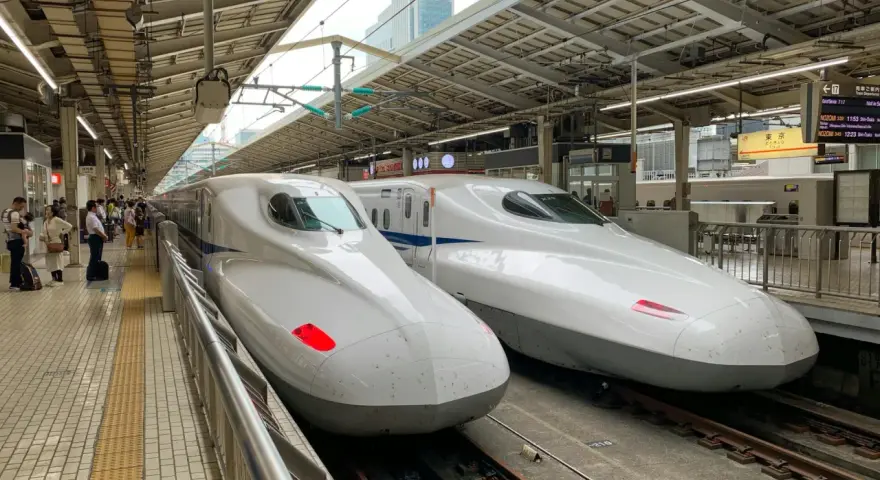 Dwa białe pociągi Shinkansen stojące na peronie, gotowe do podróży.