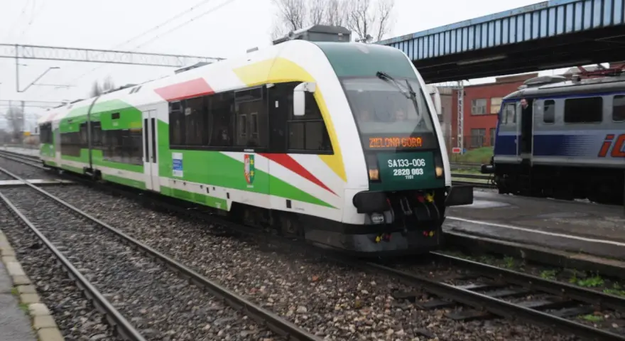 Pociąg z napisem "Zielona Góra" na torach, z zielonymi i białymi pasami na karoserii.