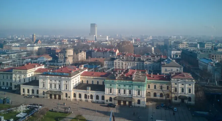 Widok na dworzec główny z tablicą "Kraków Główny". W tle miejska panorama.