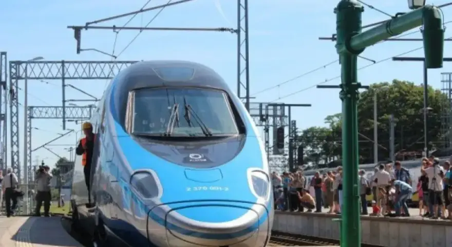 Błękitno-szary pociąg Pendolino na peronie, ludzie czekają na podróż. Oznaczenie Pendolino w rozkładzie jazdy.