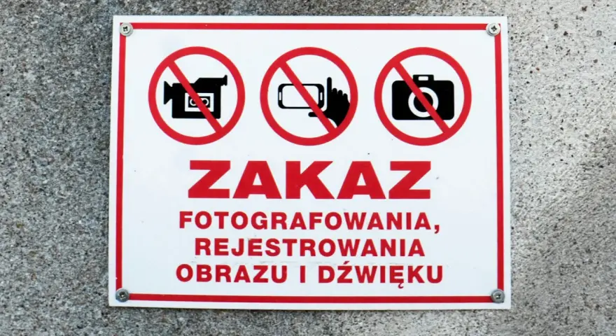 Tabliczka z czerwonym obramowaniem informuje o zakazie fotografowania, rejestrowania obrazu i dźwięku.