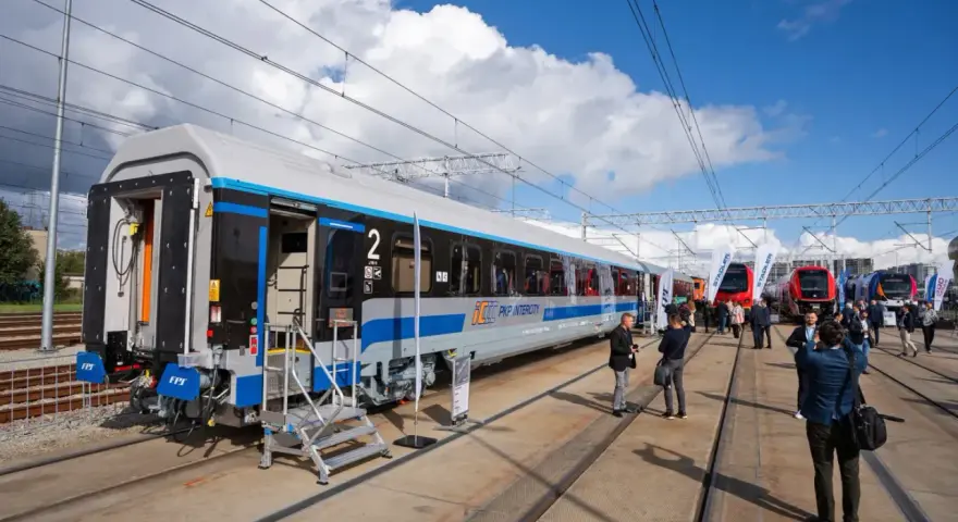 Nowy wagon PKP Intercity z niebieskim pasem, gotowy na podróż. W tle inne nowoczesne składy ec.